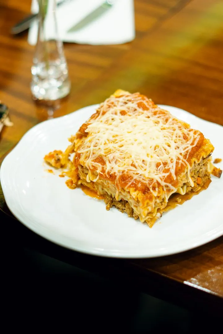 Porción de lasaña gratinada en plato blanco