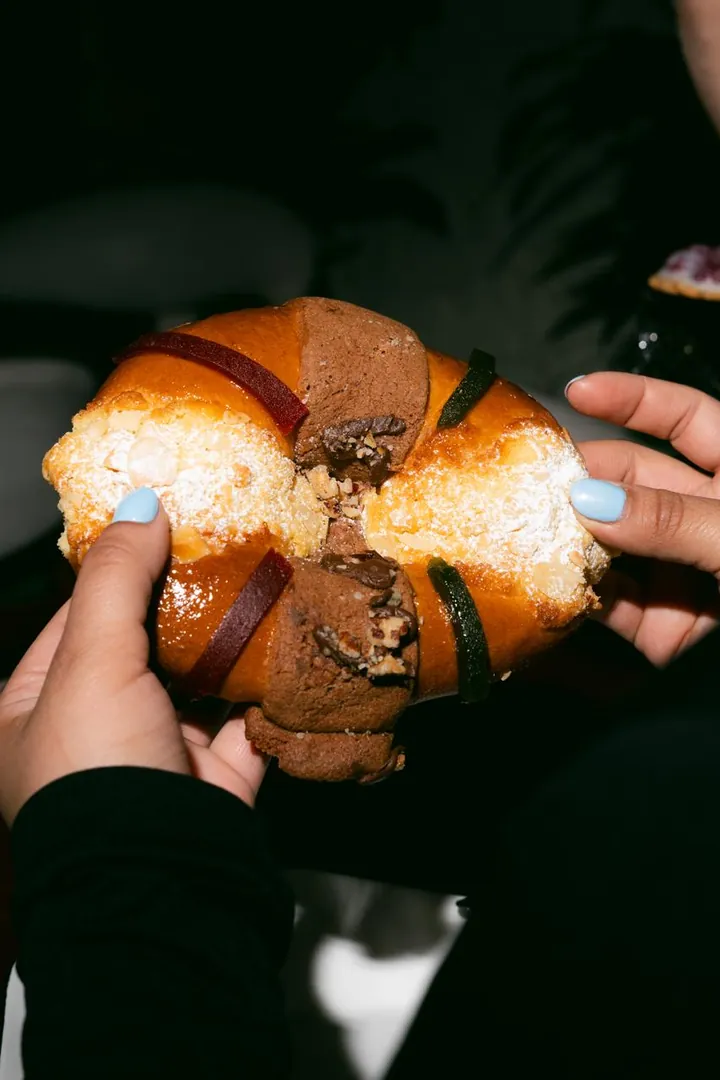 Manos partiendo una rosca rellena de chocolate