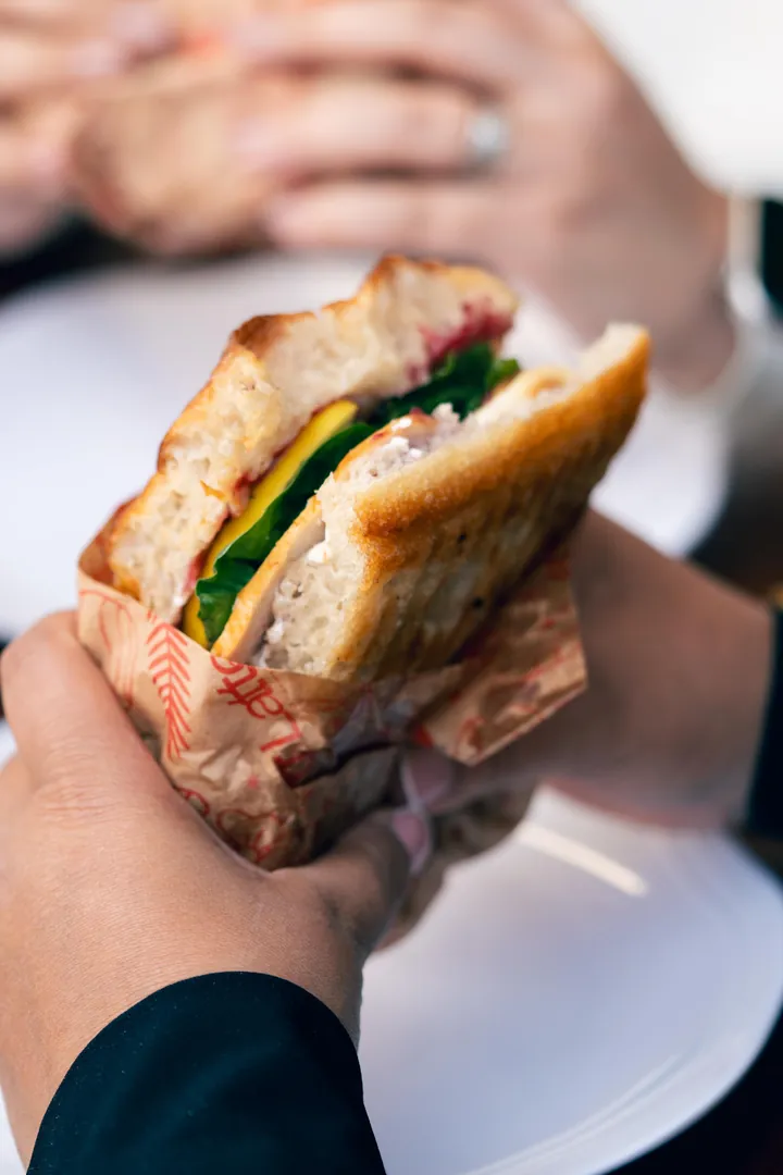 Panini tostado envuelto en papel sostenido con la mano
